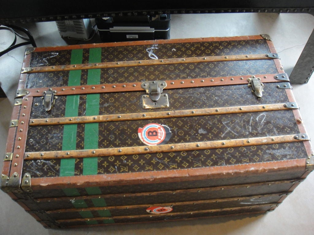 This is a large steamer trunk armoire by Louis Vuitton.  It has two green stripes and a green F.A.E stamp on one side.  Other stickers are from First Class TransAtlantique portage in 1960.  All the hardware works very well.  The leather handle has