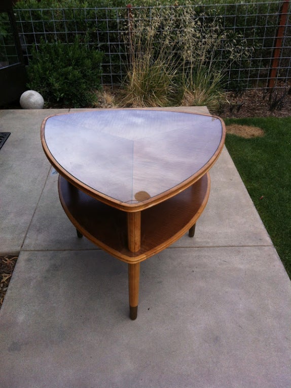 Two-tiered maple mid century side table. Figured maple inlaid with brass and brass sabot. Glass top.

Lazlo Hoenig was an Austro-Hungarian architect, interior designer, and furniture creator who trained in the Bauhaus in the 1920's and worked in