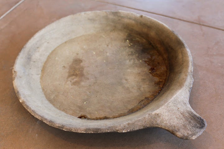 Stone food service tray from India. Carved from a single block of sandstone with an elongated handle. Two available, $650 each. Measurements: 3