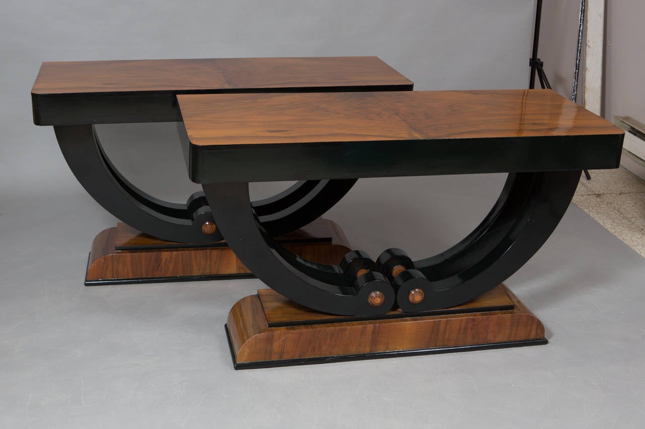 Pair of Art Deco ebonized walnut consoles with swooping supports and curved base.