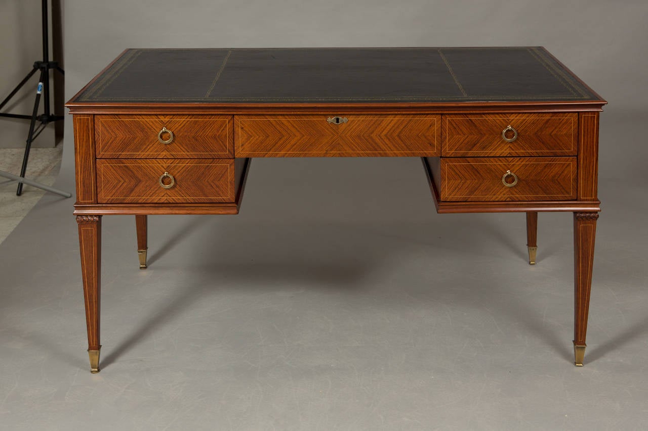 Mahogany black leather top bureau plat with 5 drawers and brass sabots finishing tapered legs. Gilt accents surround the leather with bull ring pulls on the drawers. Inlay detail on the back.
Center drawer opening height - 25.5