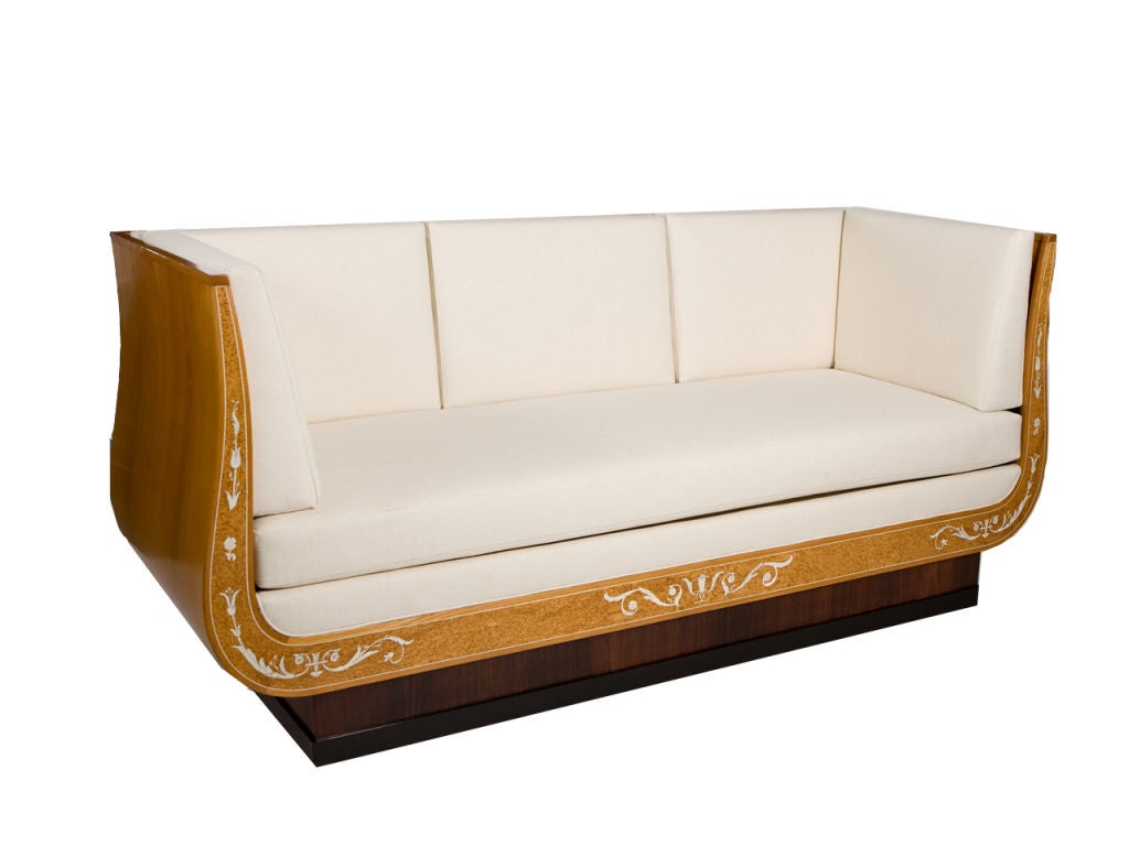 Elegant sofa designed by Carl Malmsten (1888-1972) and retailed by Nordiska Kompaniet. Classical form with gracefully curved sides and open frame back. Burled veneer with ivory/bone inlay, ebonzied molding and fitted cushions. CM brand on underside