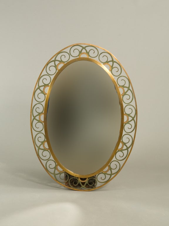 French Art Deco style brass beveled mirror with painted iron scroll work.