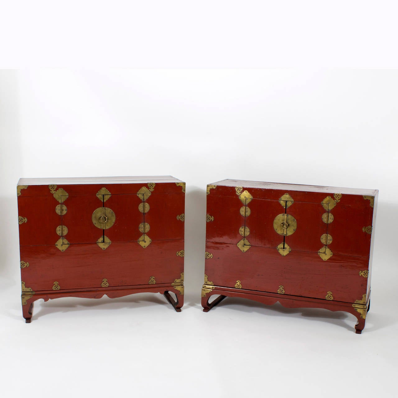 Pair of vintage red lacquer Chinese chests or night stands with dovetailed cases decorated with decorative pierced brass hardware, a scalloped base and modified Chinese Chippendale bracket foot, 2 small doors conceal an open storage compartments.