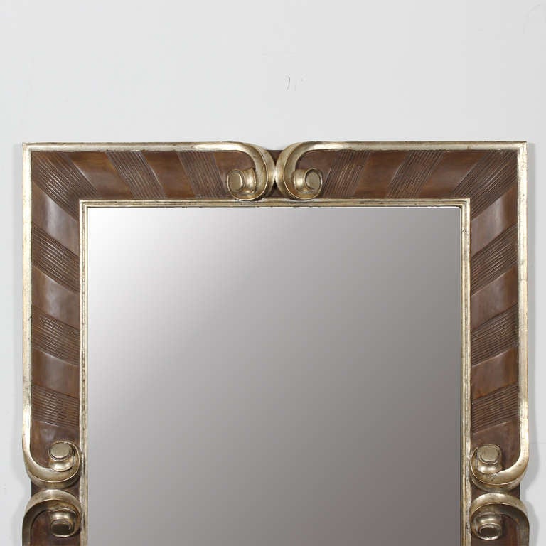 A rectangular shaped mirror with silver gilt molding, and carved scrolls, inscribed details alternate around the frame. The frame has an overall rustic yet sophisticated design. Possibly by Harrison Gil.

   