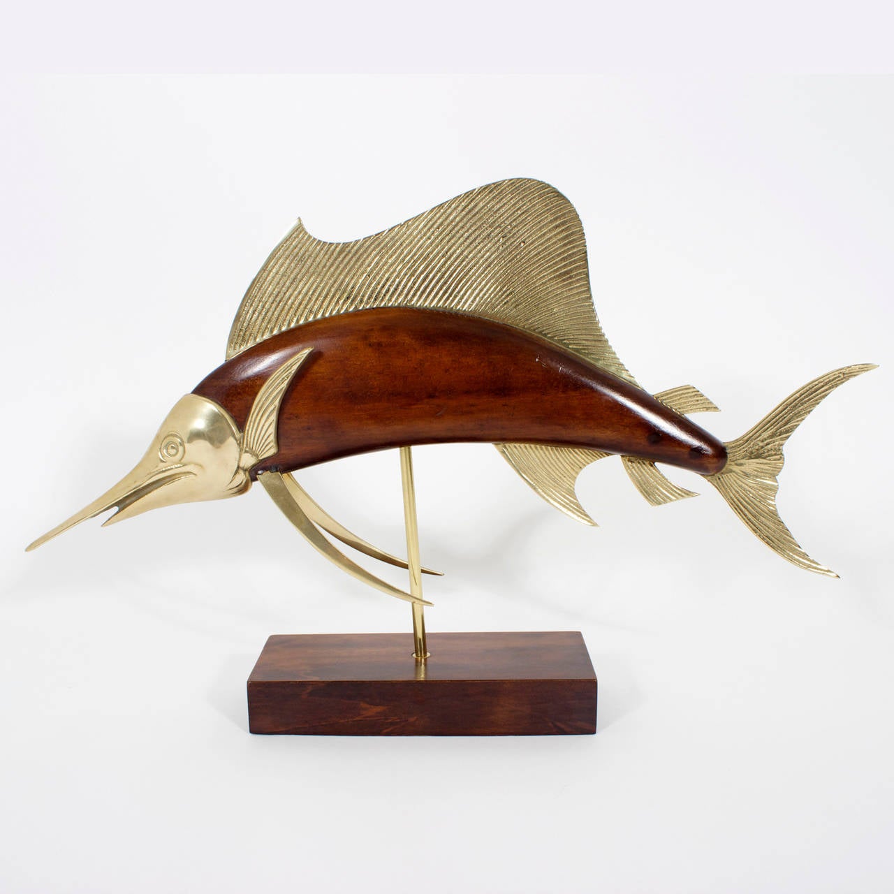 Whimsical sailfish sculpture executed in mahogany with brass accents mounted on a brass rod over a hardwood base. Labeled Frederick Cooper.

