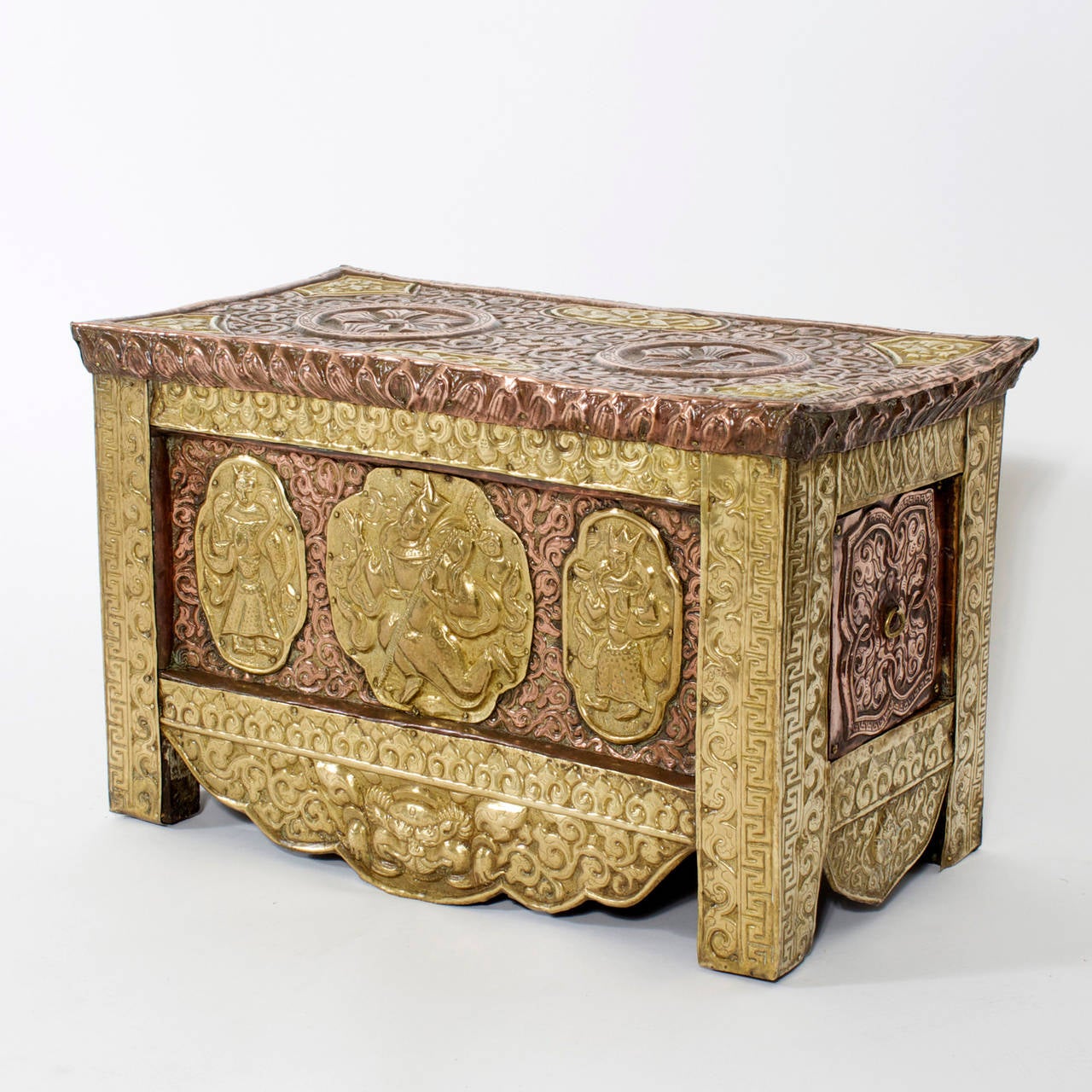 Exotic one drawer faux box made of wood and completely clad with elaborate brass and copper repousse with Greek key, foliate and deity embossing. Custom-made for storing your valuables. The top does not lift on this box the secret drawer is the only