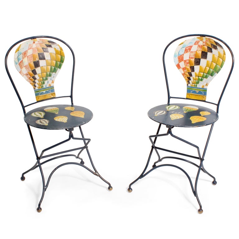 How charming is this...a three-piece metal cafe set, two chairs and a table, painted in bright colors, now faded beautifully, with a stylized air balloon back splat and painted air balloon seats. Small brass painted balls terminate the legs. Totally