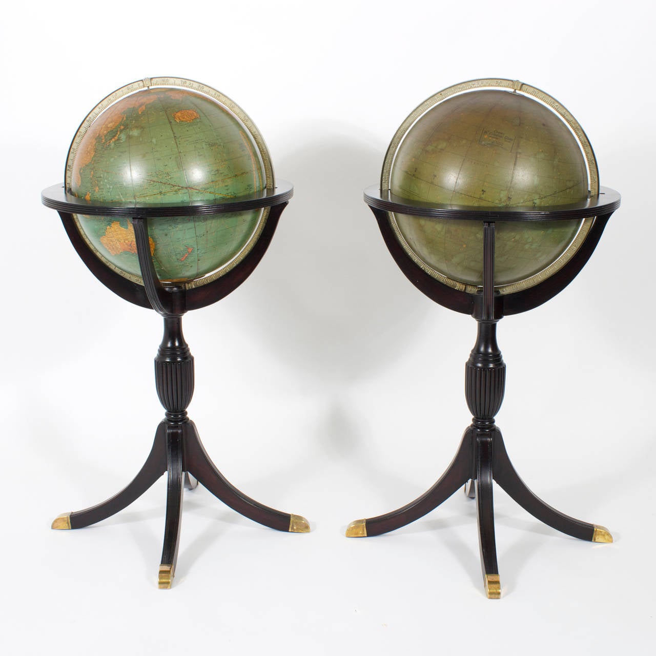 A rare pair of vintage scholastic globes one terrestrial and one celestial, mounted in ebonized Hepplewhite style mahogany stands with brass feet. The glass globes with decoupage are labelled Cram. Minor repair to one globe. Perfect for a library or