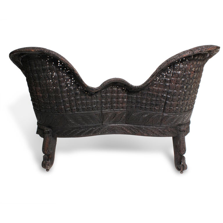 This is a wonderful small scale Anglo Indian carved settee. The carving is a bit primitive, which gives the settee a more country or rustic flavor.
Mythical creatures adorn the legs and arms, the remainder carved with vines and foliage. 

All