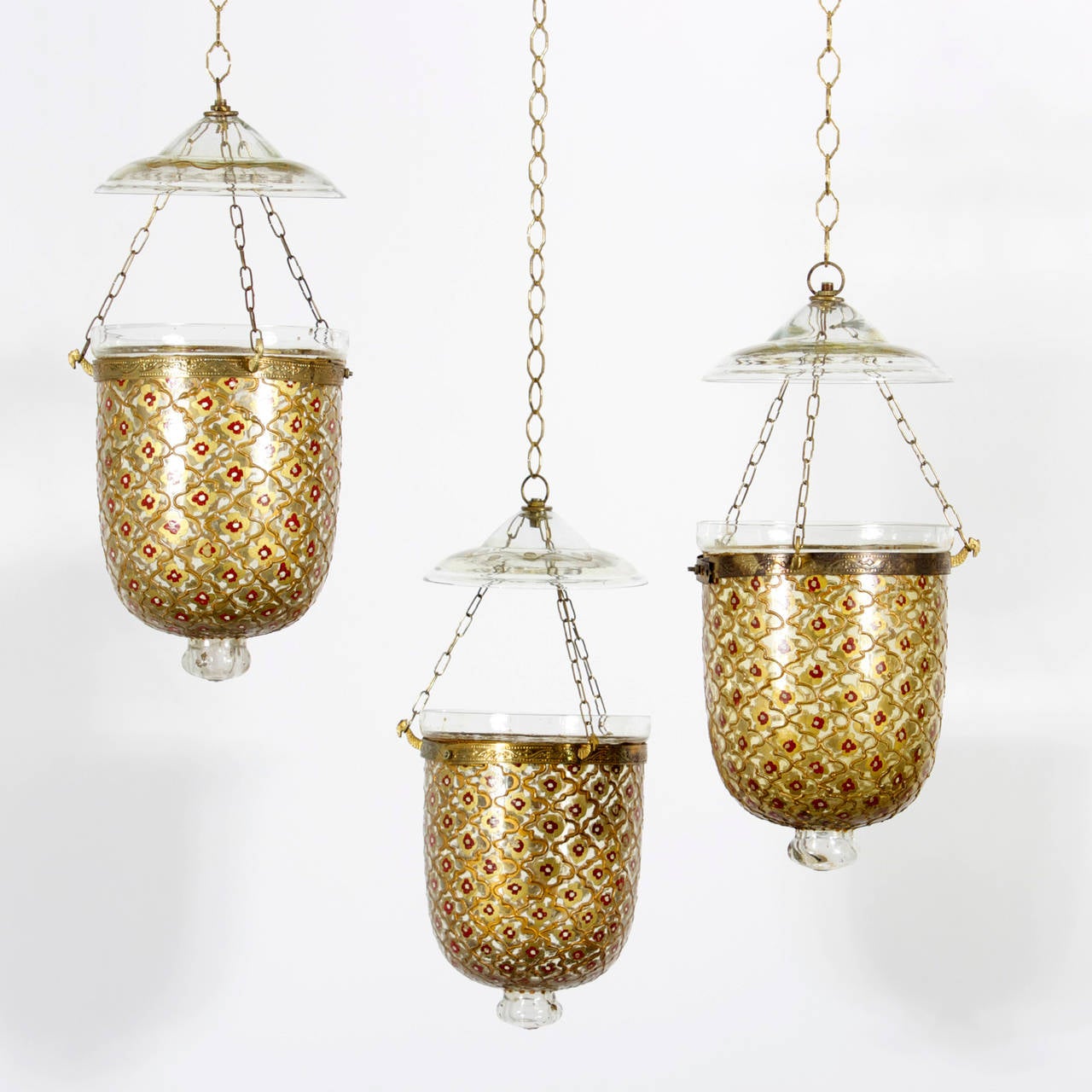 Exotic Anglo Indian bell jar candle lanterns or pedants decorated with red flowers inside gold cartouches and having brass bands with camel heads chained to  shaped and decorated smoke bells. 10 available. Priced Individually.