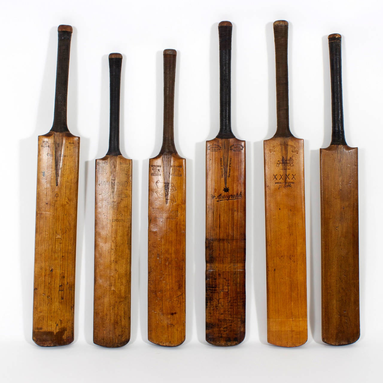 A collection of five cricket bats in assorted hues of willow wood. Stamped by the manufacturers, with nicely wrapped handles and having the romance and patina of a time bygone time. Longest 34