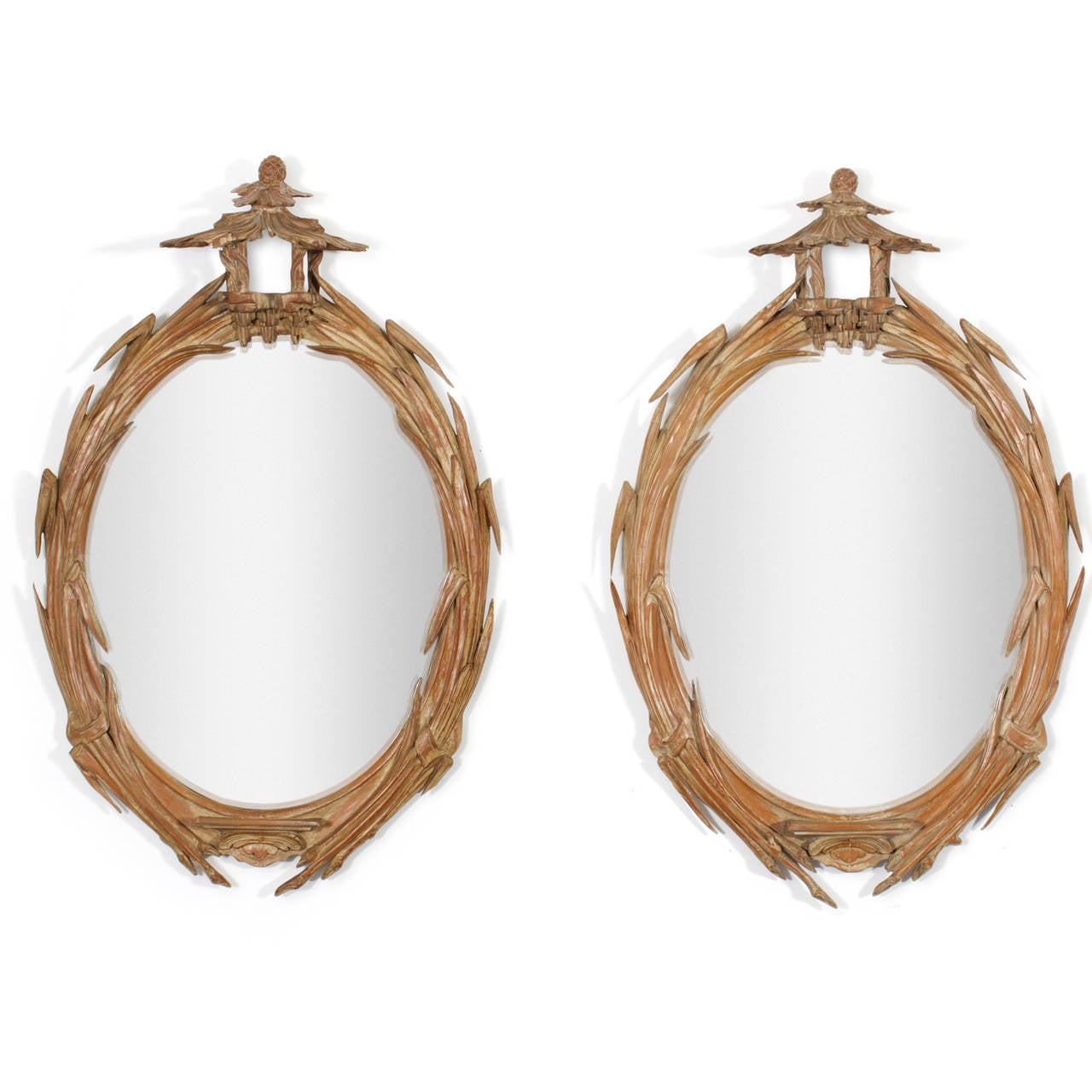 Unusual, mid century pair of Italian carved wood mirrors featuring reed and leaf motif oval frames with whimsical pagoda tops and pineapple finials all in a highlighted white wash finish.