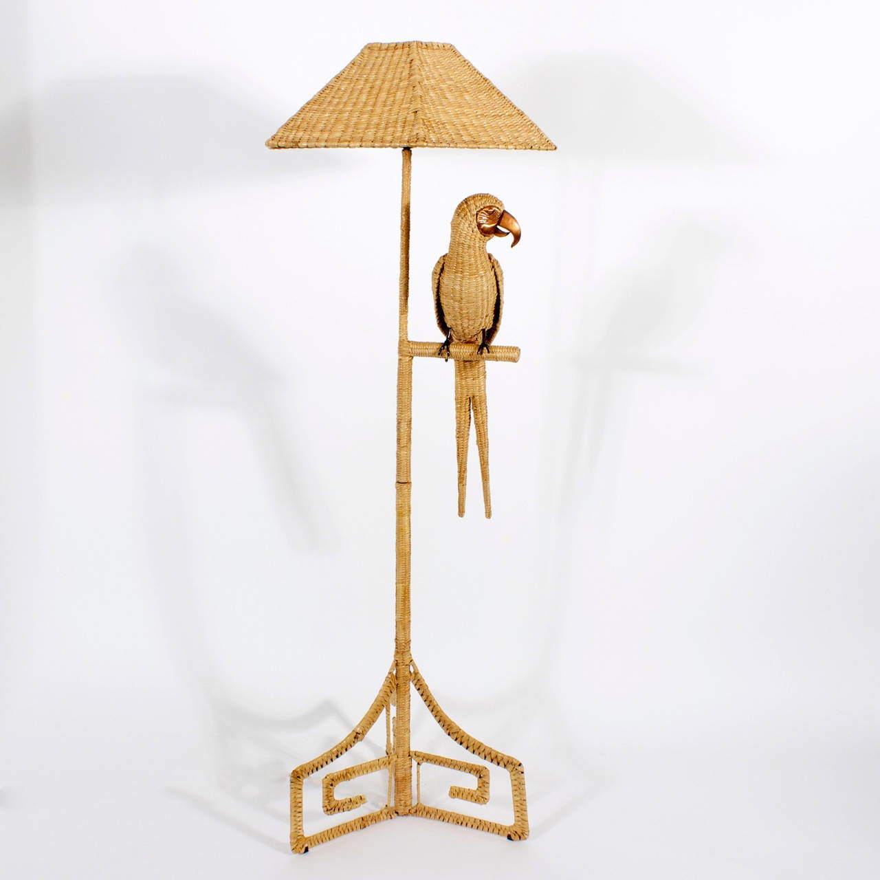 Whimsical Mario Torres floor lamp constructed with an iron frame wrapped in (chuspata) rush and featuring a woven rush parrot on a perch with copper beak, eyes and claws. Three Greek key legs and matching woven rush shade. This floor lamp proves