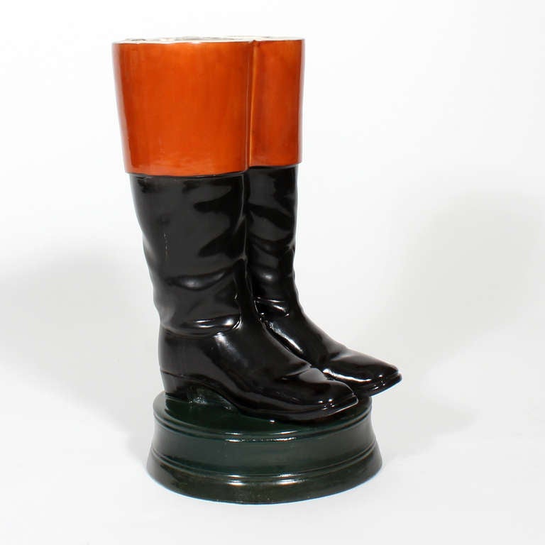This is an amazing piece, salmon cuffed black boots, on a deep, dark green base, almost 19th C military in feeling.  The base is fitted with a drainage hole to remove built up water. The lip of umbrella stand and 3 inches of the interior have worn,