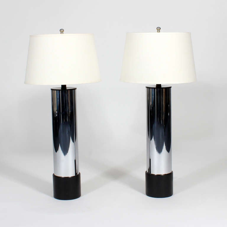 This is a pair of high style Mid-Century Modern cylinder lamps in chrome-plated steel, with black leather bases. Tall, stately and sophisticated. Newly wired. 

