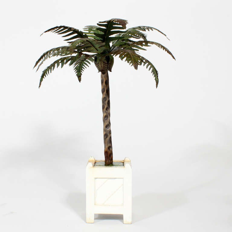 A pair of painted tole palm tree candle holders, in weighted painted metal bases, with just the right amount of rusting and aging to the surface of the palm fronds and trunks. Great decorative size.

