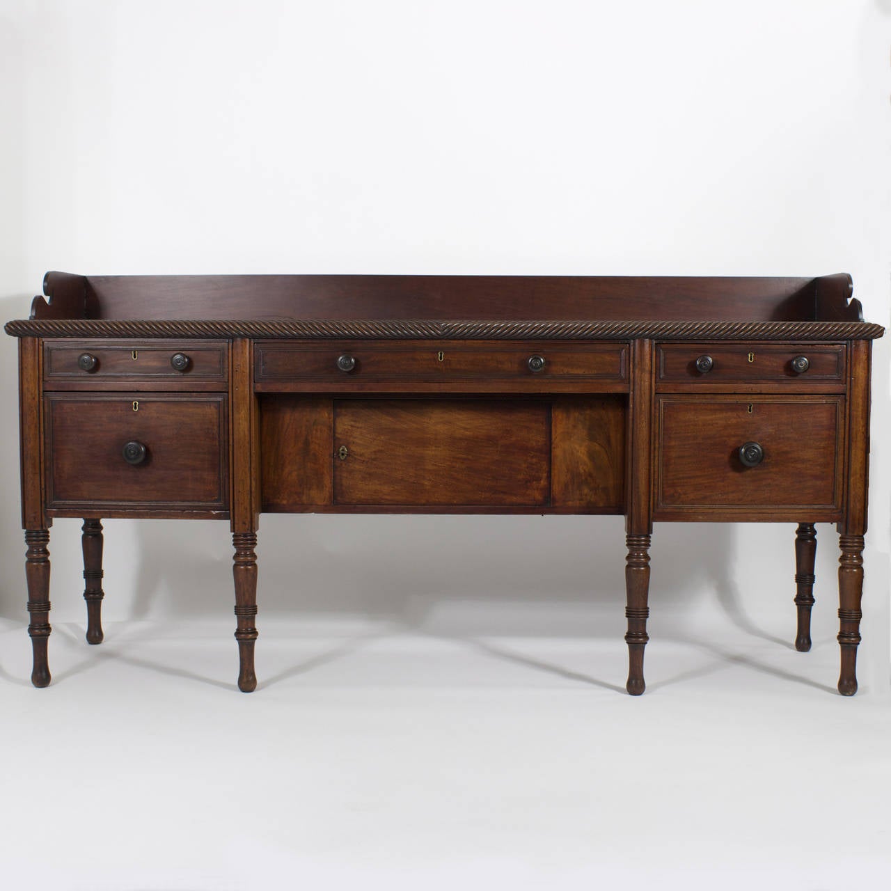 A 19th century, English mahogany sideboard or server with a real British Colonial vibe.  With all of the features that you want to see in a sideboard, 3  drawers and 3 doors (2 faux drawers (doors) flanking a central door, including a well
