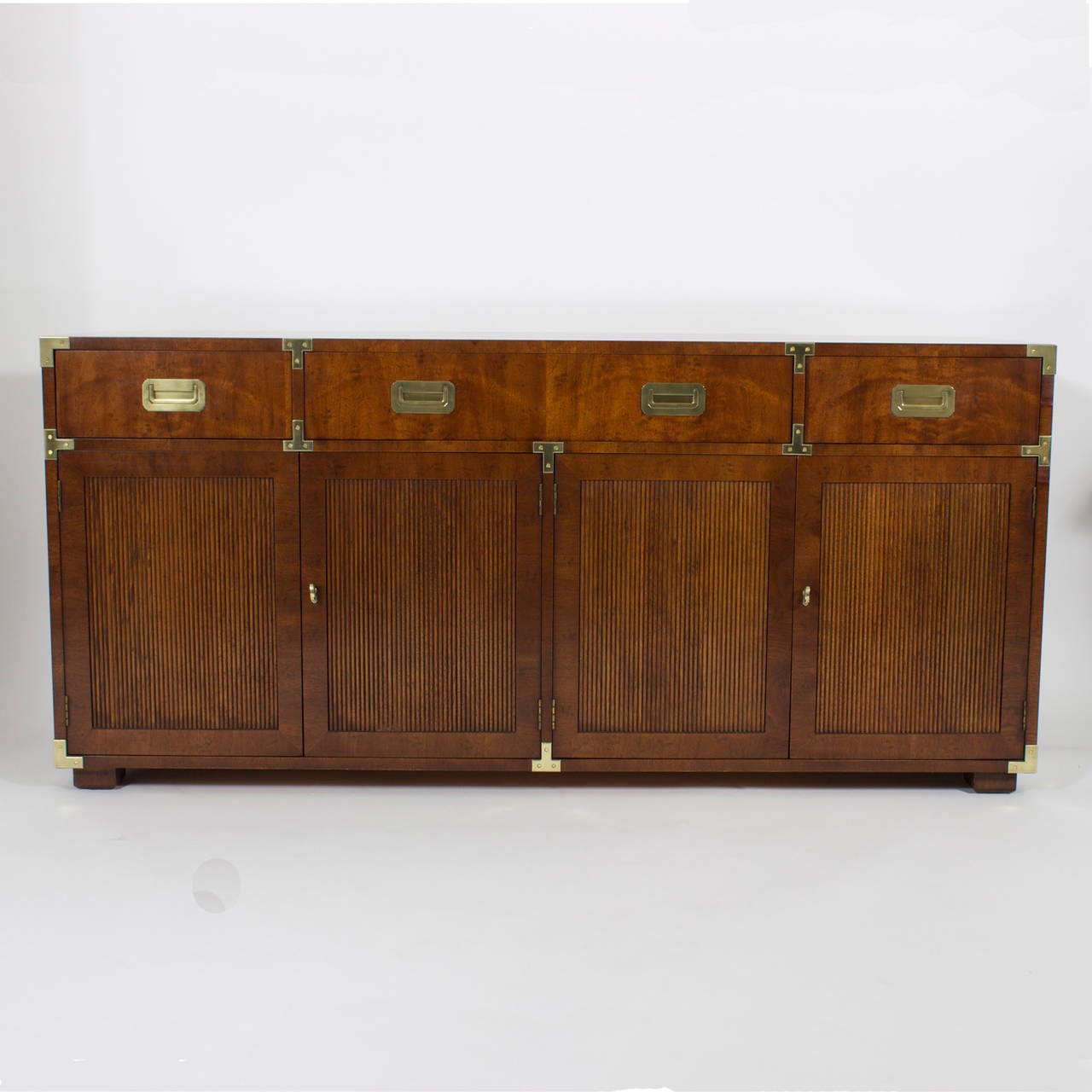 Four-door, four-drawer Henredon campaign style sideboard, cabinet, credenza or dresser, with a Mid-Century Modern twist, featuring beaded doors, solid brass hardware and plenty of storage space. Perfect marriage of traditional and Mid-Century Modern