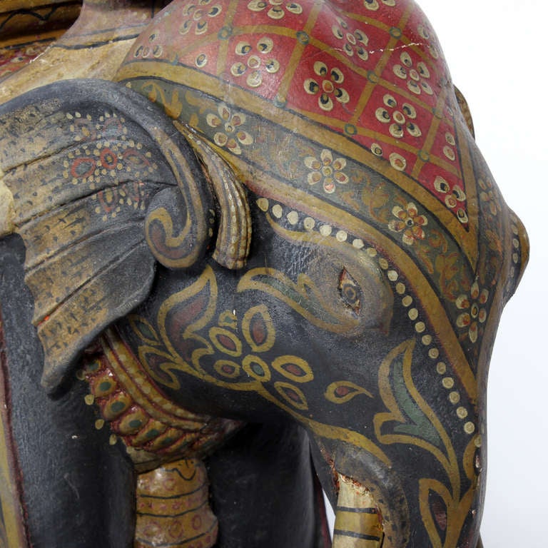 Magnifique éléphant indien en bois sculpté, décoré à la peinture, avec son cavalier, sur une base à roues peinte en rouge. Les détails de la peinture sont incroyables. Une œuvre de grande envergure, impressionnante et délicieuse.

   