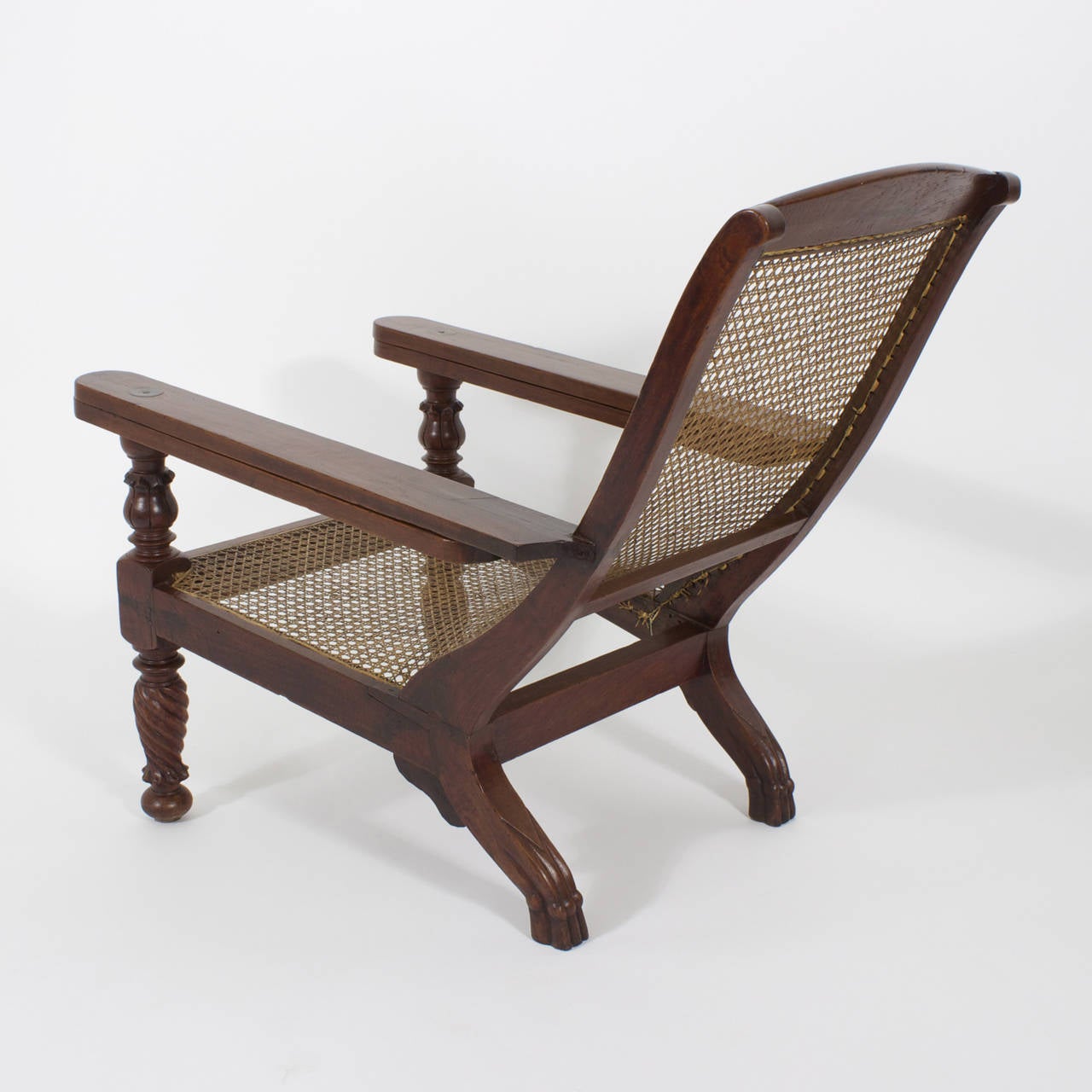 Inviting, classic Anglo Indian mahogany plantation or planters chair with turned and carved front legs, slightly paneled skirt, animal paw hind legs and swing out arms. Sit back and enjoy life. Newly polished. 60