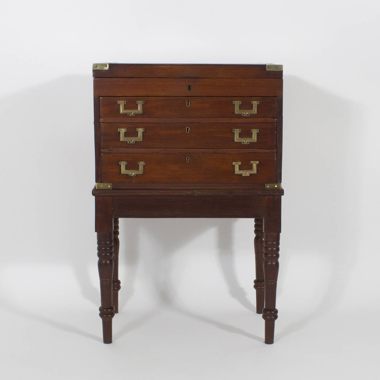 An uncommon 19th century, English mahogany three-drawer Campaign chest for silverware with hinged lidded top, presented on a custom-made later mahogany stand with turned legs. Perfect for maintaining an Empire while dining in style. Newly polished