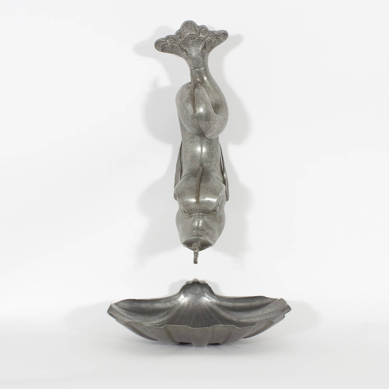 Highly decorative and fanciful dolphin fountain, pewter lavabo, depicting the sailors mythological dolphin form with a spout in its mouth, hung over a shell shaped bowl, all with an aged and polished finish.
