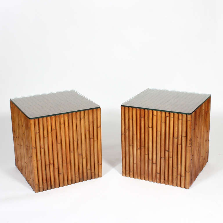 A pair of end tables or nightstands heavily constructed with a series of standing solid wood dowels carved and finished to look like bamboo. Close to 300 pieces are visible on the tops of the tables, a very 1970s cool look. Glass tops are available