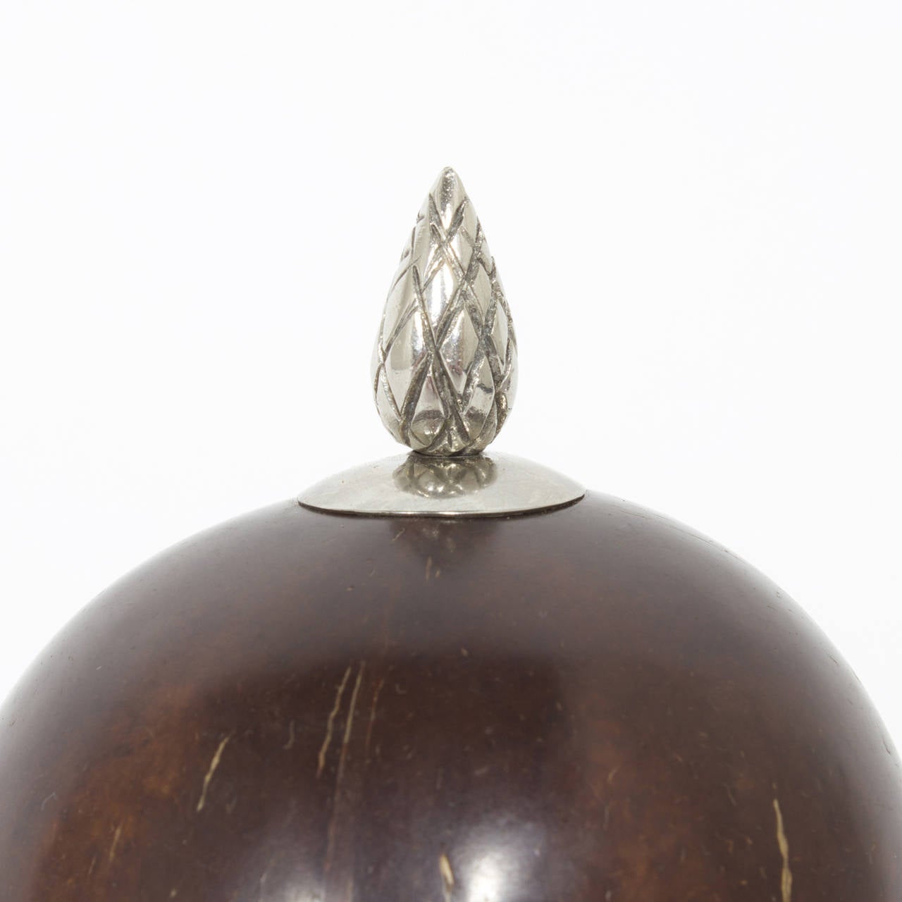 Chocolate colored coconut box decorated with finely crafted silvered metal work, including pineapple finial, bracelet style twisted rope cuffs with a jewelry type catch, all mounted on a goblet style base. Interior is finished to complete the