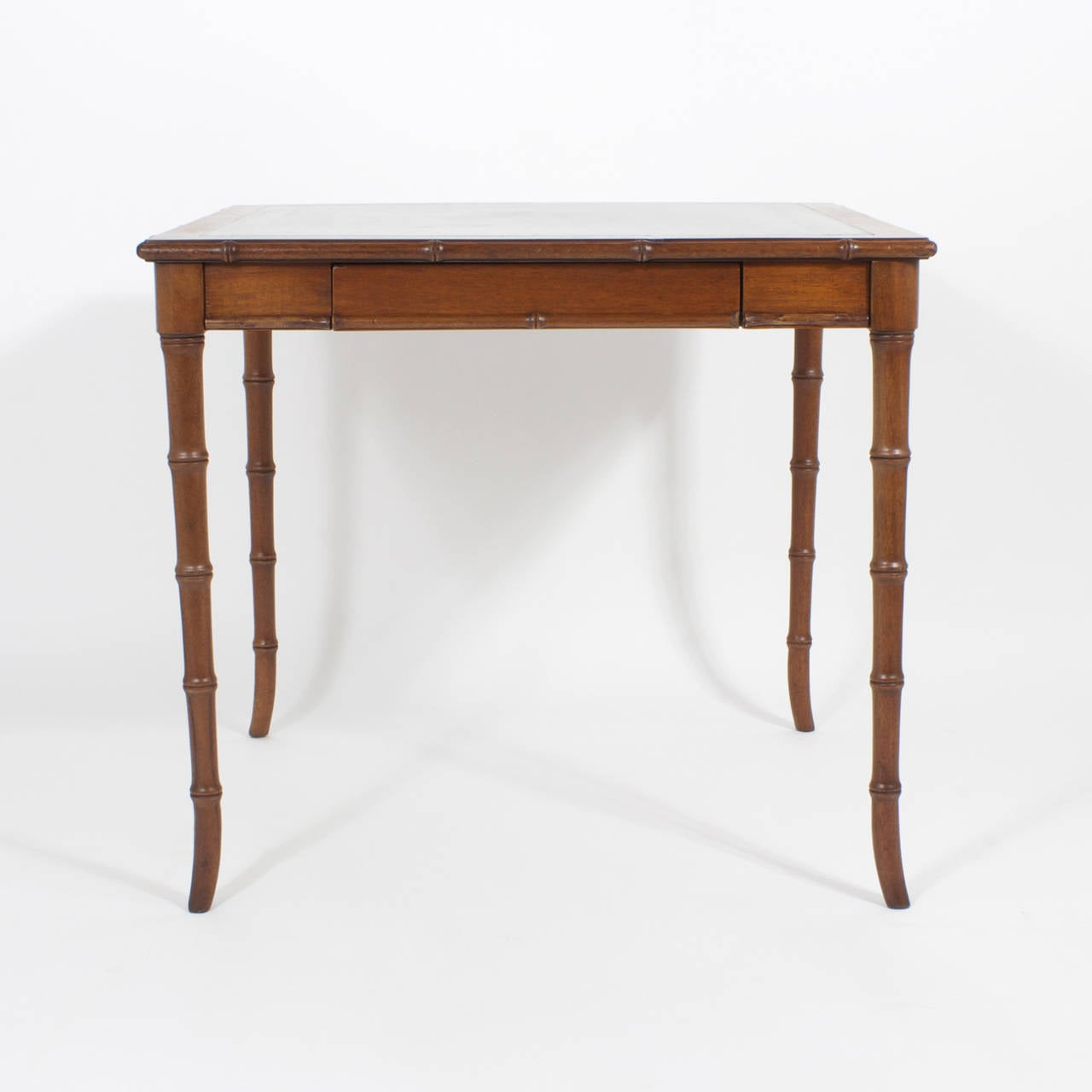 Tradition melds with modern in this regency style,  mid century faux bamboo  games table,  featuring elegant faux bamboo legs and a tooled leather top. Newly polished.