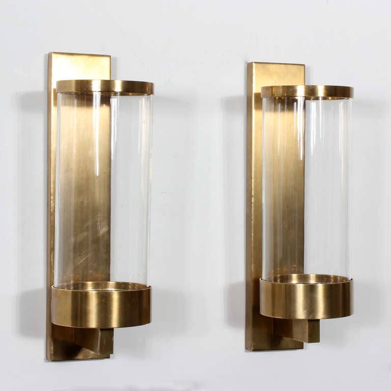A pair of modern design brass and glass wall sconces, with robust back plates and brass banded cylinder shaped glass shades. Labelled Chapman, 1978. These sconces have a strong architectural element.