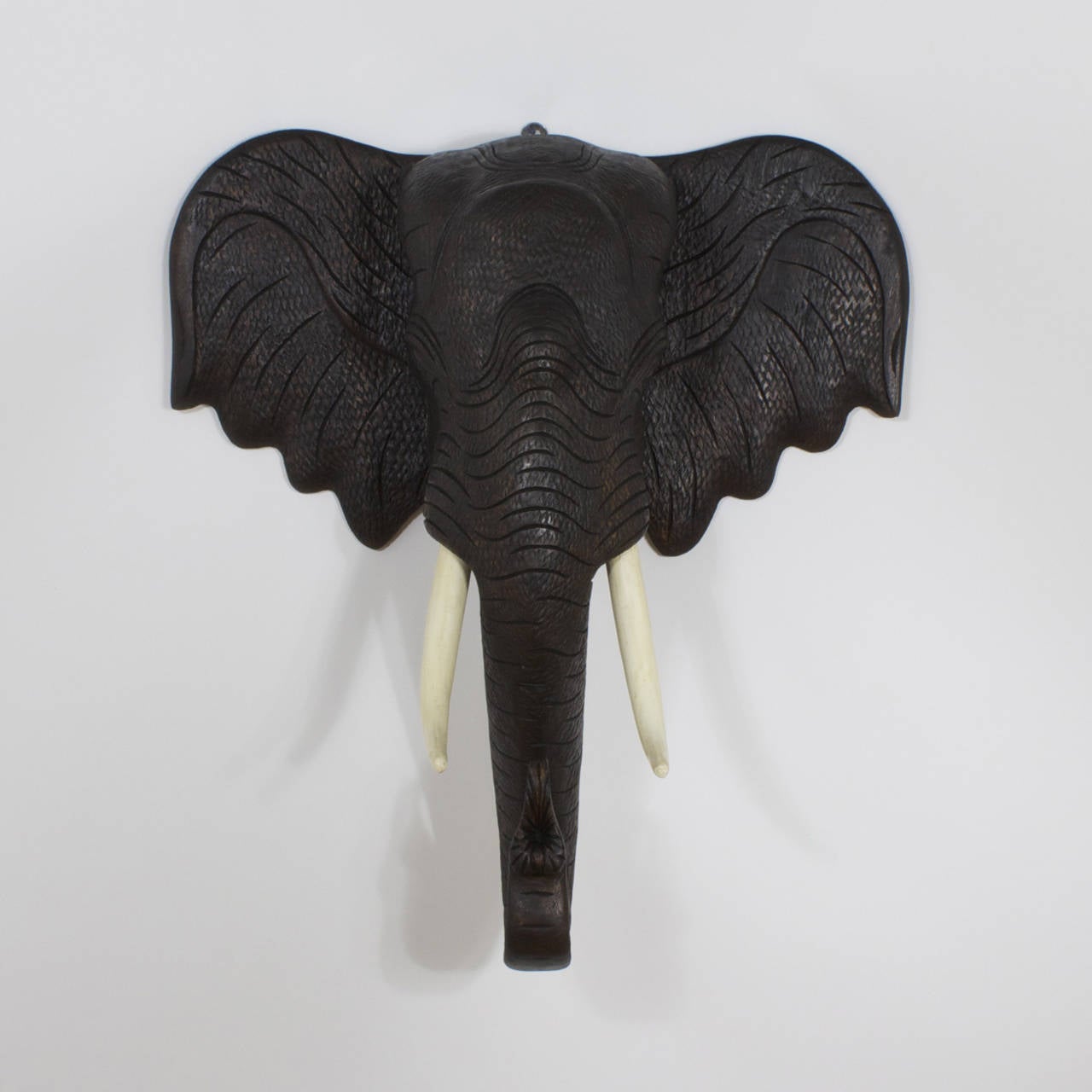 This large carved hardwood elephant head has amazing life like skin texture and striking realistic presence. Capturing the spirit and wisdom of this majestic and mysterious creature with those all-knowing eyes. Featuring carved wood tusks, turned up
