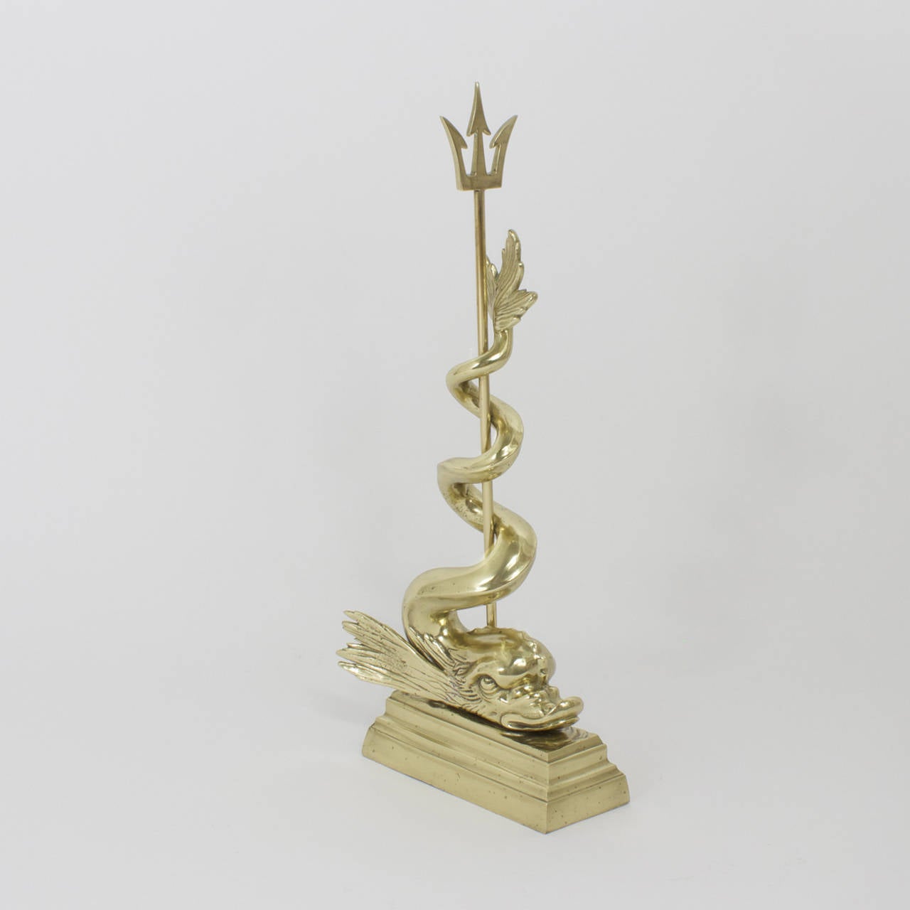 Nautical, cast brass, antique doorstop with hand polished and lacquered finish. Depicting a mythological grotto dolphin style sea serpent coiled around Poseidon's trident which is then mounted on a multi tiered classical plinth. This is certainly a