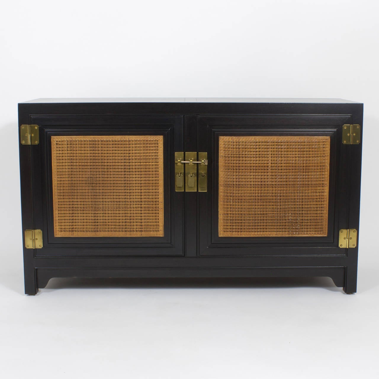 A Midcentury two-door cabinet or sideboard with strong asian influences and an unusual addition of the caned wicker doors. With plenty of storage this makes for the perfect fit under your flat screen television or as the serving sideboard it was