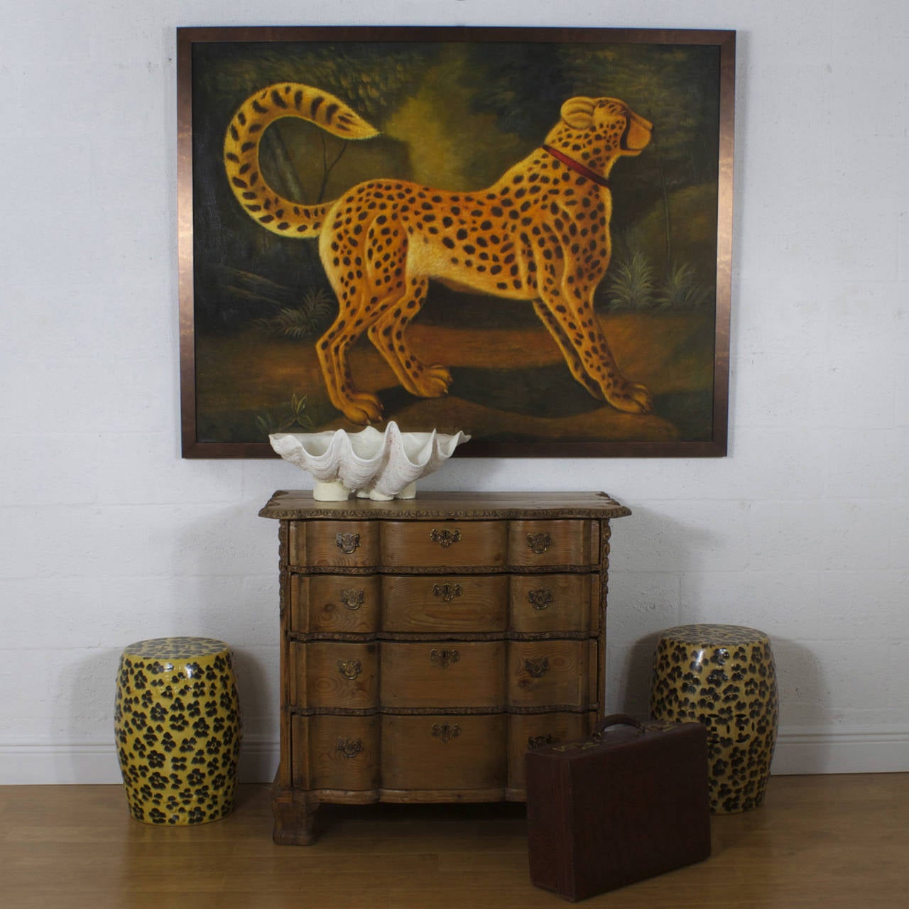 A large dramatic oil painting on canvas, of the speedy cheetah, with a rustic, and folk quality. Set against a jungle landscape and signed Reginald Baxter on the lower right, this painting has a contrived aged look with crackled varnish that was