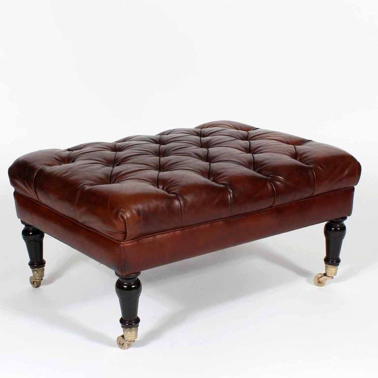 A really wonderful tufted leather ottoman, with well turned legs and brass cup casters. It definitely has the British Colonial for den or library vibe. Beautiful patina to the very thick leather, very nice upholstered, all and all, a very sweet