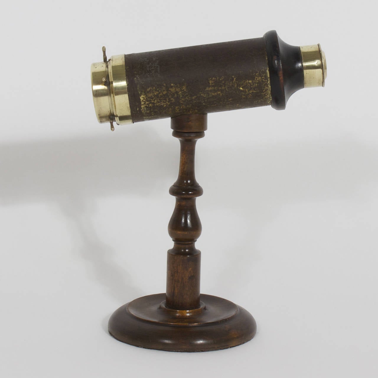Kaléidoscope ancien avec oculaire en laiton et un mécanisme de rotation à cylindre en bois et cuir en forme de roue de bateau. La base classique est en bois dur tourné et poli. Présent à l'origine dans les salons de la haute société, le kaléidoscope