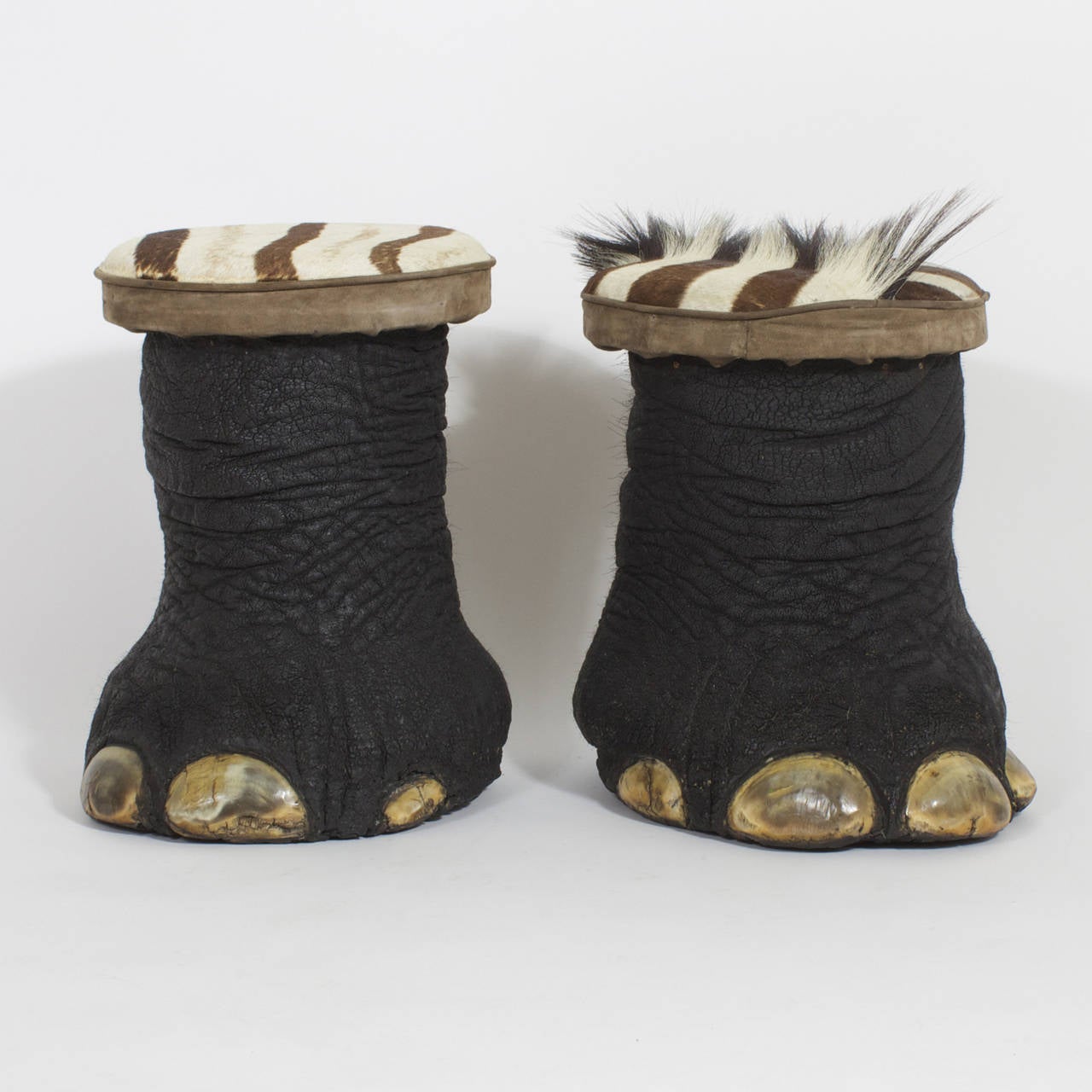 Organic pair of taxidermic elephants feet re purposed as foot stools or benches with seats upholstered in Zebra that is trimmed with suede. We are not condoning the hunting of Elephants or any other animals but these where made from an elephant that