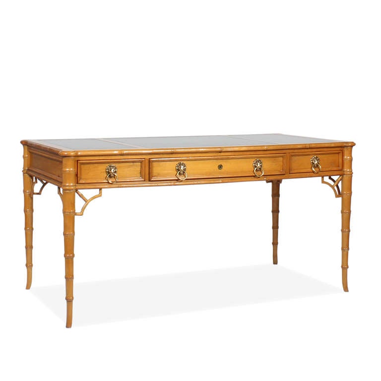 A wonderfully designed desk, with faux bamboo legs, and molded top. Three working molded drawers, with lion head pulls and 3 panels on the reverse. Great aged pine surface, with a three panel lightly tooled leather top. Labelled Baker. A very