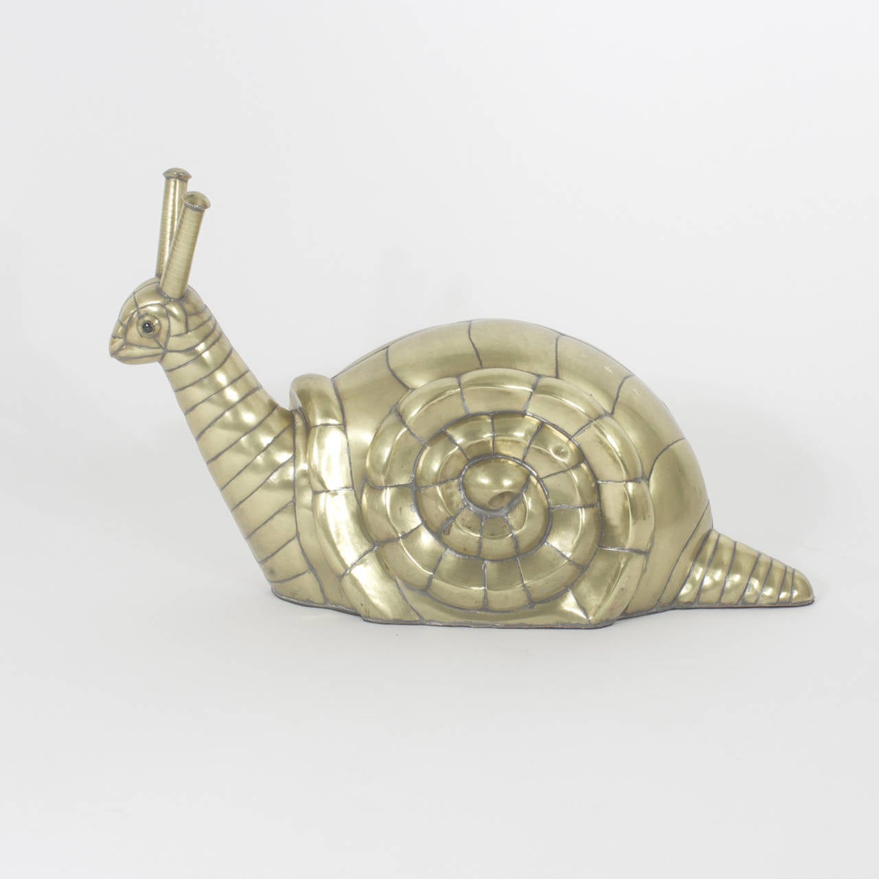 Perky Bustamante brass snail sculpture with glass eyes, formidable antennas and a subtle confidence. The brass has been polished to a warm glow and lacquered for easy care. Newly polished.