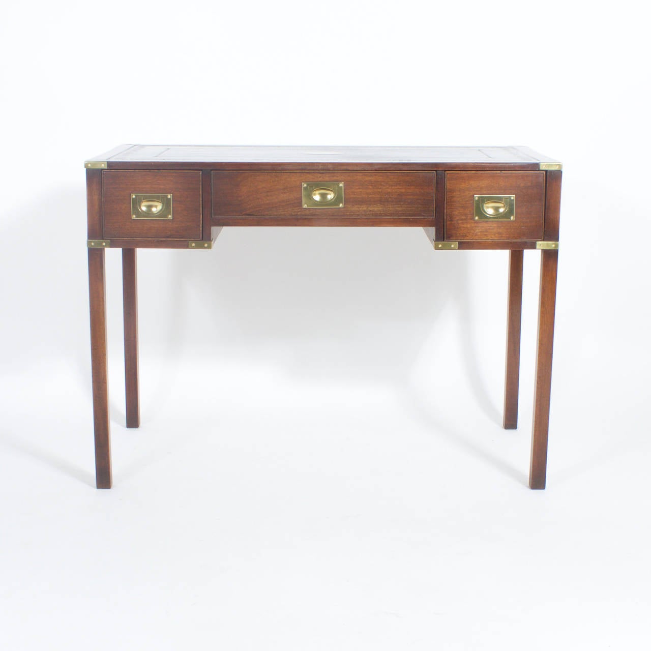 English style mahogany Campaign writing table or desk with brass campaign style hardware. The top is dark green tooled leather with the added feature of a brass plaque waiting to be engraved. Mid-Century simplicity with English Campaign warmth.