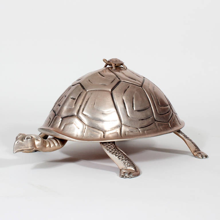 A large-scale and amusing cast aluminum turtle cutting board with back riding baby turtle handle. A Mid-Century Modern version of an old world domed cutting board serving piece. Certainly a conversation piece with practicality. Add it to your