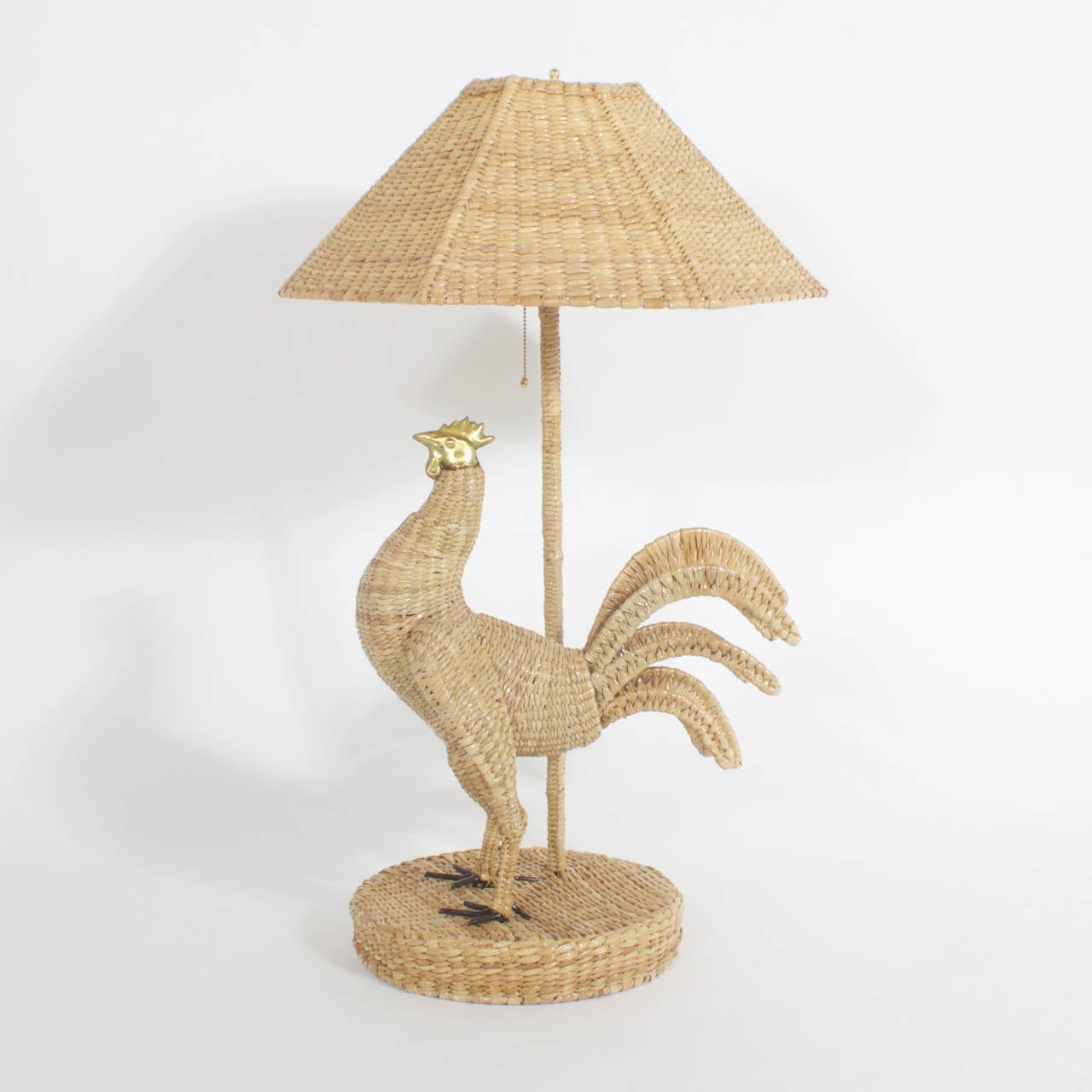 Pair of whimsical Mario Torres Rooster table lamps constructed of a metal frame tightly wrapped in wicker or reed. These lamps feature brass heads with metal talons and your choice of wicker or linen shades. These birds are strutting their stuff