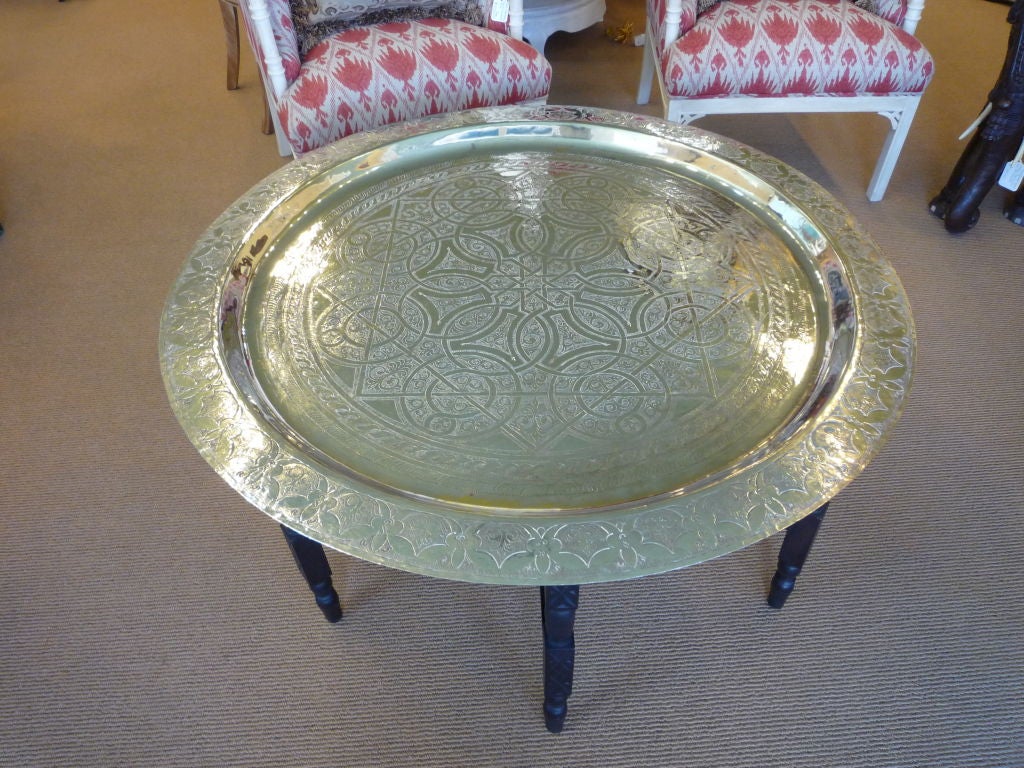 A huge hand etched silver plated tray on a collapsible carved and ebonized wood base. The silver tray table is very sturdy.

