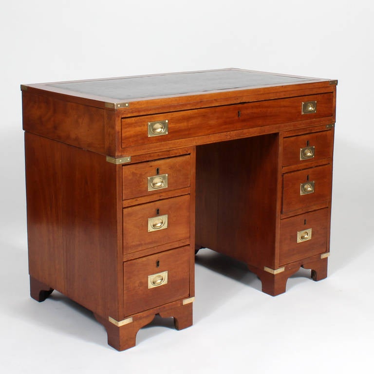 A 19th century, antique three-part English campaign desk, in mahogany with an old if not original leather top, and a beautiful bracket base. As was often done in the 19th century. The campaign hardware was added later, when the desk was used for