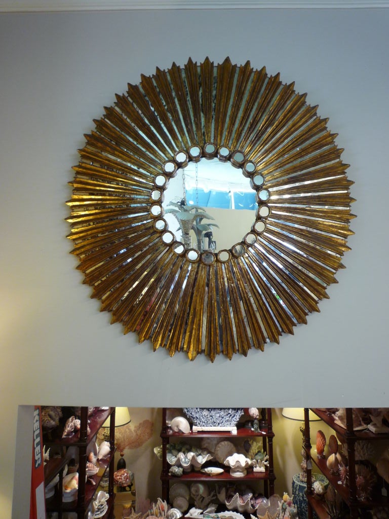 A beautiful large round carved and gilt sunburst mirror with great surface. Small mirrored panels alternate with giltwood rays, around a central mirror. The mirrored panels showing signs of age and wear. A great decorative statement.

 