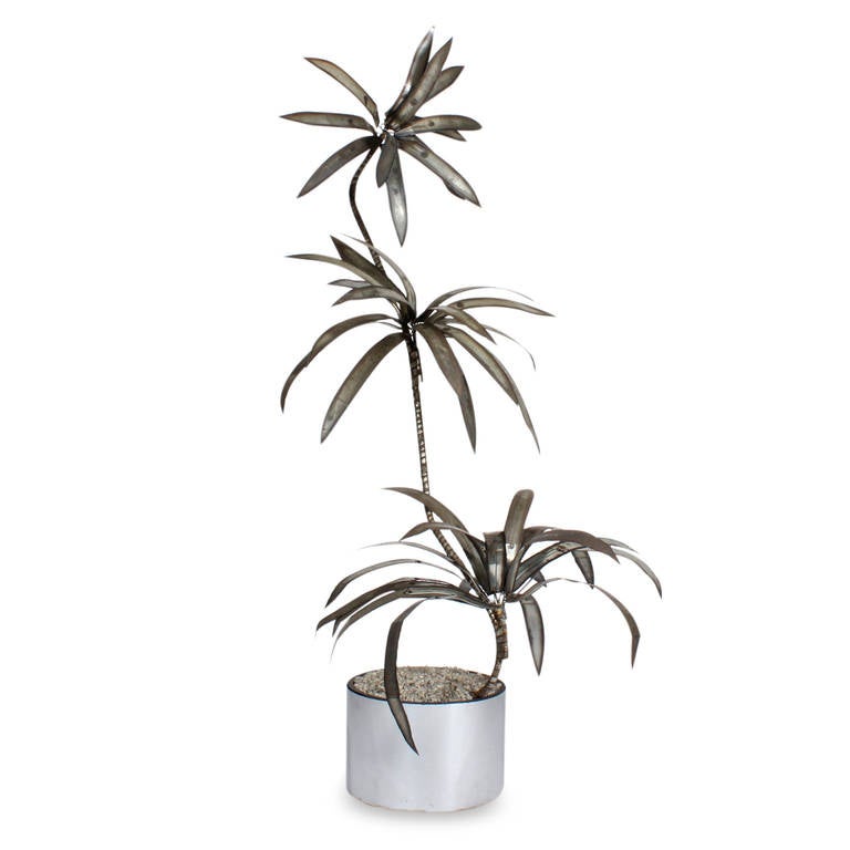 An unusual midcentury hand-cut steel model of a dracaena palm in a hip silver laminate planter. Highly decorative, dramatic and true to form. Fabulous pitting and patina. A wonderful tropical element for the most interesting of decors.

