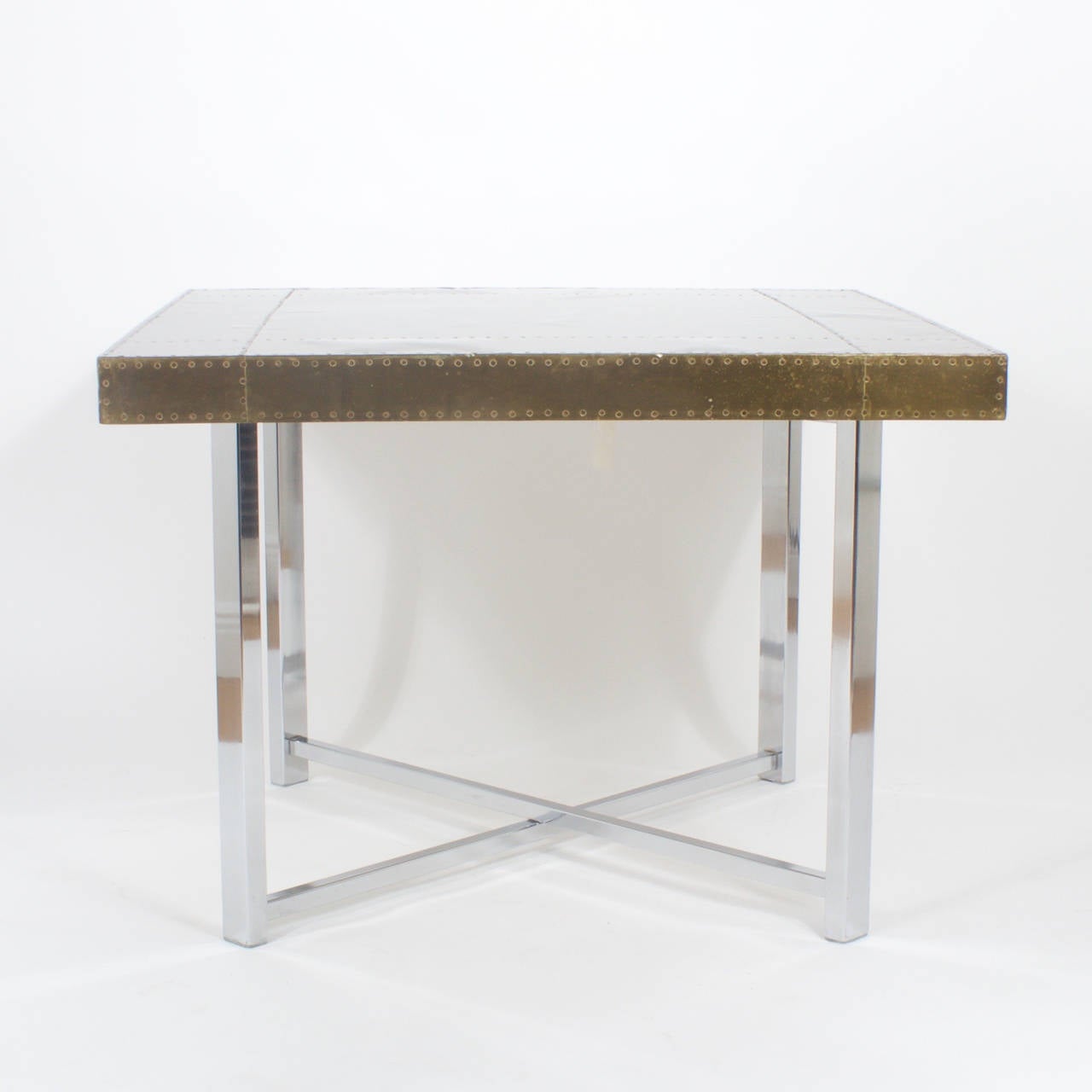 Midcentury Campaign style brass and chrome games or card table with a removable top and folding legs for easy storage. The square top has a sculptural element with patched brass sections riveted down in an Industrial way. Great combination of cool