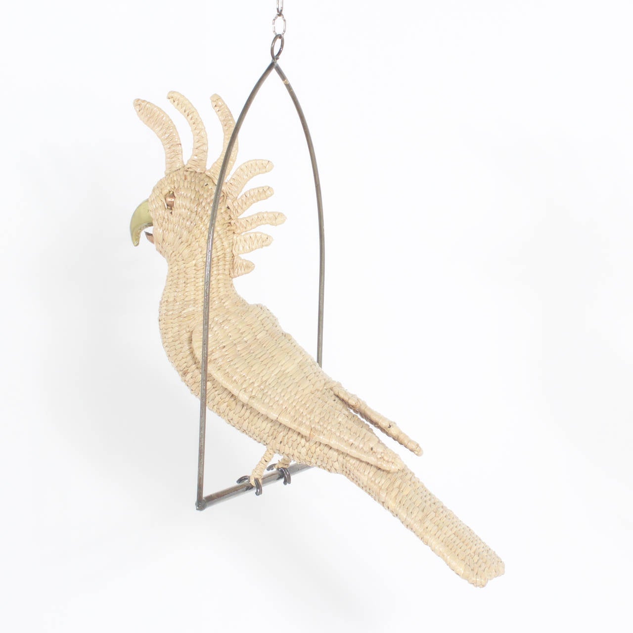 Amusing midcentury Mario Torres wicker Cockatoo perched on a metal swing. Having a brass face and beak. He appears to be saying something cheeky.