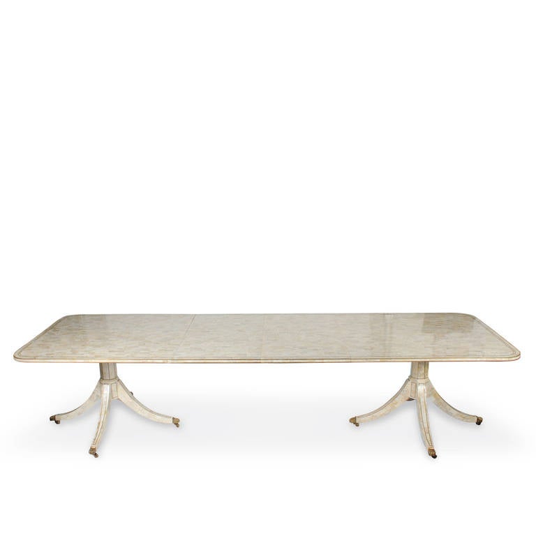 A large and rare tessellated stone dining table with two brass banded pedestals and splayed tripod legs. An impressive top showing the small hand cut blocks of stone,  all banded in brass, two leaves of 22.25 each,  extend this table to an